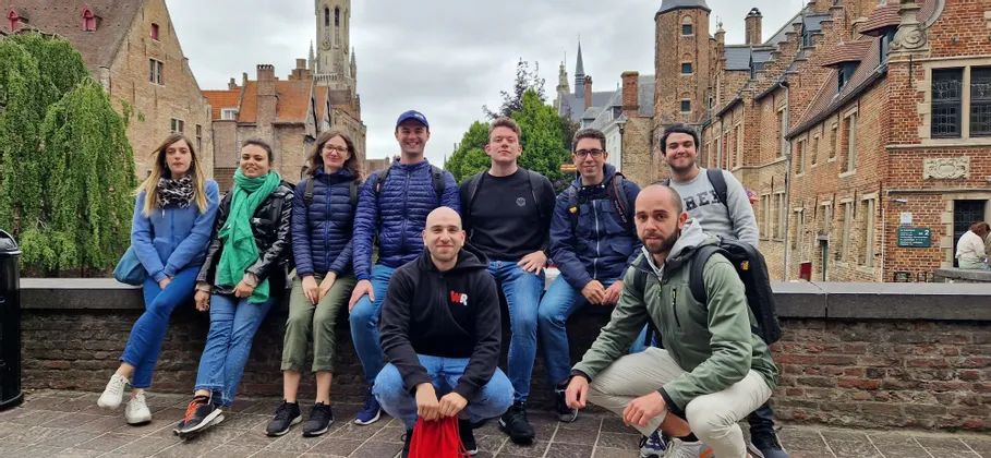 WeRoad Gruppenreise: Menschen posieren auf einer Steinmauer, im Hintergrund historische Backsteingebäude und ein Turm.