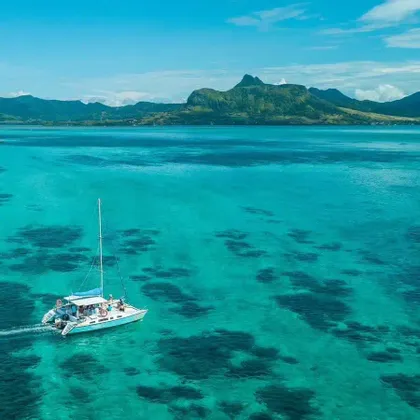 Veduta aerea di un catamarano con a bordo un gruppo WeRoad che naviga su acque turchesi verso un'isola montuosa.