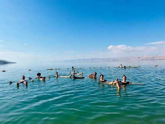 Eine WeRoad-Gruppe treibt entspannt auf dem Rücken in einem ruhigen Meer unter strahlend blauem Himmel.