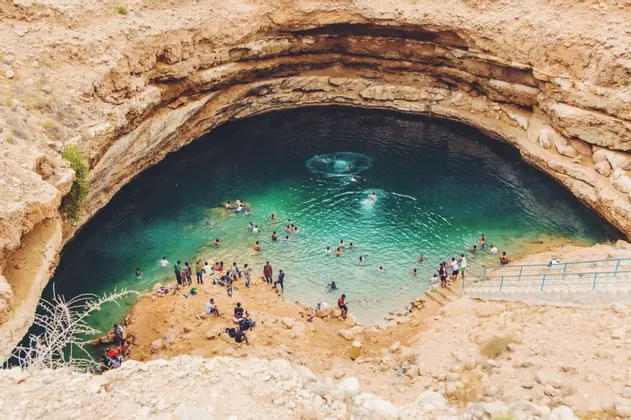 Eine WeRoad-Gruppenreise beim Schwimmen und Entspannen in einer großen Cenote mit türkisfarbenem Wasser, von oben betrachtet.