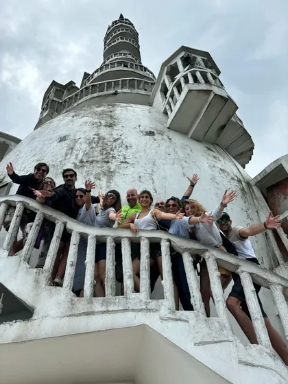 Eine WeRoad-Gruppe posiert und winkt auf der Treppe eines großen, weißen Kuppelgebäudes unter bewölktem Himmel.
