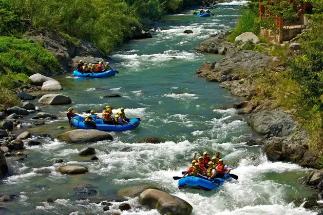 Un viaggio di gruppo WeRoad: rafting su gommoni blu lungo un fiume immerso nella vegetazione lussureggiante.