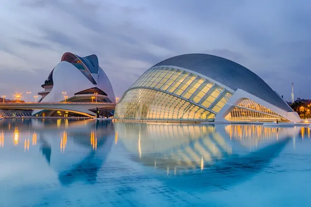 Due moderni edifici architettonici illuminati riflessi in una tranquilla piscina d'acqua al crepuscolo.