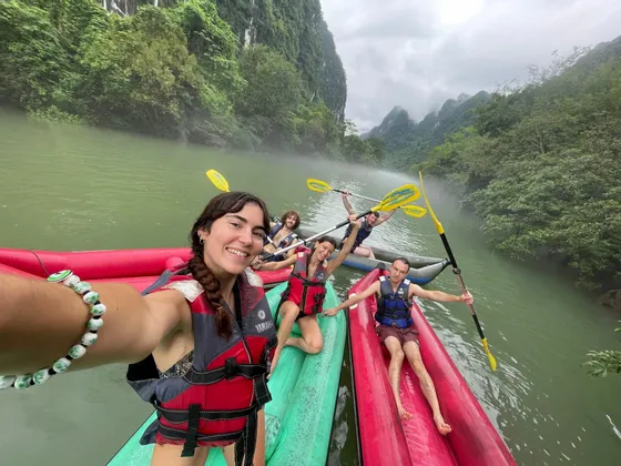 Un gruppo WeRoad si scatta un selfie mentre fa kayak su un fiume nebbioso, circondato da montagne verdi e lussureggianti.