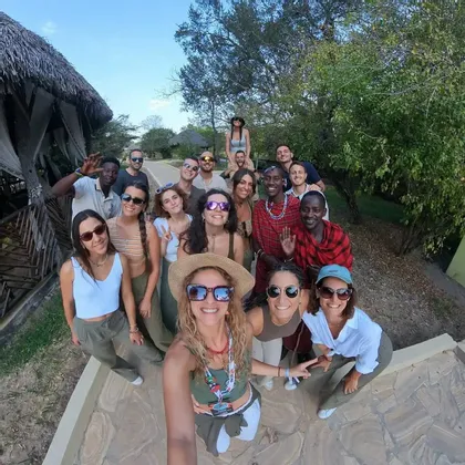 Un gruppo WeRoad si fa un selfie con due uomini locali in abiti tradizionali su un sentiero di pietre lastricate.