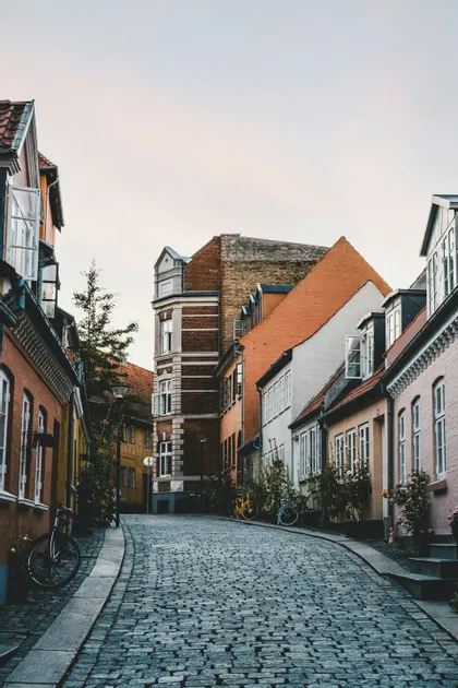 Une rue pavée sinueuse est bordée de bâtiments historiques colorés, avec plusieurs vélos garés le long.