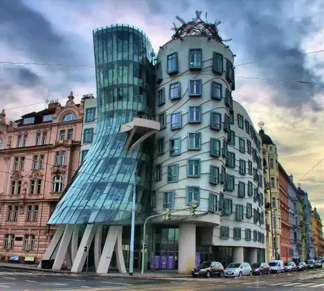 El moderno edificio de la Casa Danzante, con sus retorcidas torres de cristal y hormigón ondulado, se alza en una esquina de una calle de la ciudad bajo un cielo nublado.