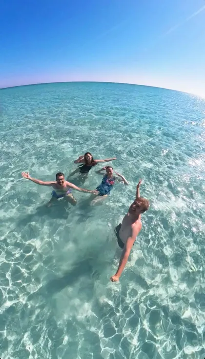 Un viaggio di gruppo WeRoad di quattro persone che si scattano un selfie mentre nuotano in acque limpide e turchesi sotto un cielo azzurro.