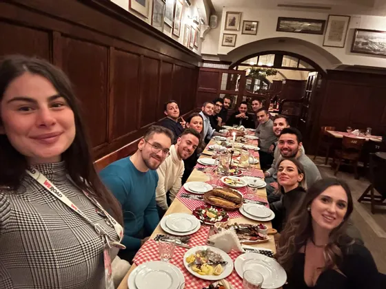 Eine WeRoad-Gruppe sitzt lächelnd für ein Foto an einem langen Esstisch in einem Restaurant.