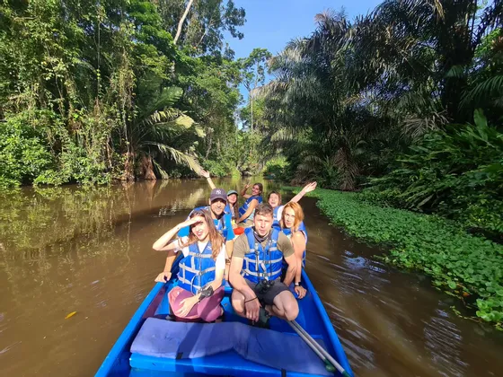 Un grupo de WeRoad con chalecos salvavidas viaja en barco por un río en medio de una exuberante selva verde.