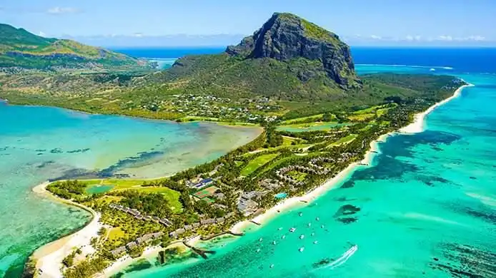 Veduta aerea di una penisola tropicale verde con una montagna imponente, circondata da acque oceaniche turchesi e spiagge di sabbia bianca.