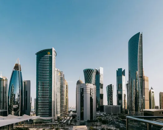 Un fitto paesaggio urbano di moderni grattacieli dall'architettura unica che si stagliano sotto un cielo azzurro e limpido.
