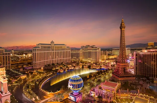Una vista aerea della Las Vegas Strip al tramonto, con la replica illuminata della Torre Eiffel e le fontane del Bellagio.