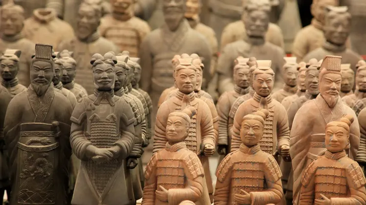 Fila di antiche statue di guerrieri dell'Esercito di Terracotta in posizione di attenti, con una profondità di campo ridotta che si concentra sul primo piano.
