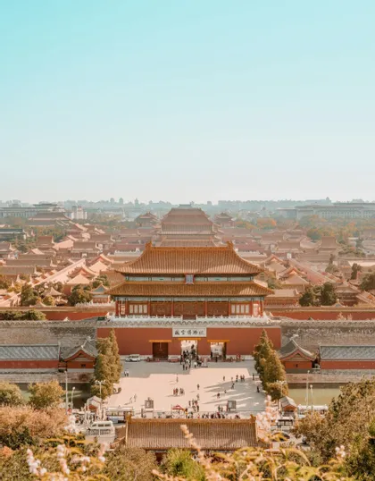 Una veduta dall'alto di un grande complesso palaziale asiatico tradizionale, caratterizzato da edifici rossi e tetti di tegole sotto un cielo sereno.