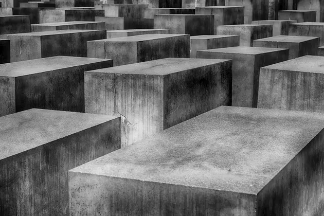Una fotografía en primer plano, en blanco y negro, que muestra numerosos bloques rectangulares de hormigón de diferentes alturas dispuestos en una densa cuadrícula.