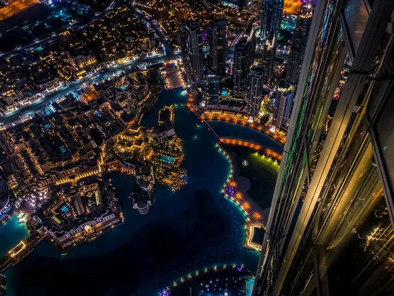 Vista dall'alto da un grattacielo su una città illuminata con corsi d'acqua e ponti di notte.