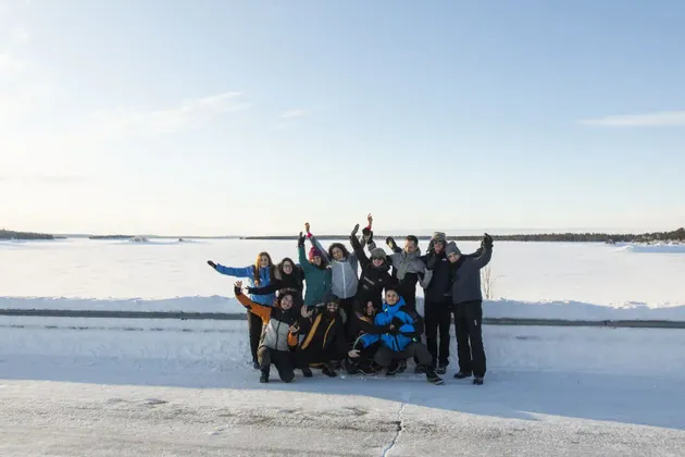 Eine WeRoad-Gruppenreise in Winterkleidung, die in einer weiten, verschneiten Landschaft unter klarem Himmel für ein Foto posiert.