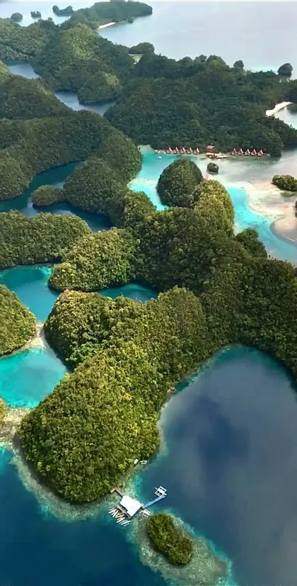 Una vista aerea di numerose piccole isole verdi sparse in acque calme, turchesi e blu profondo.