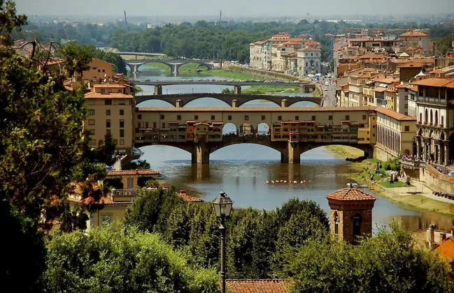 Veduta diurna sopraelevata di un ponte storico con edifici, che attraversa un ampio fiume in una città europea.