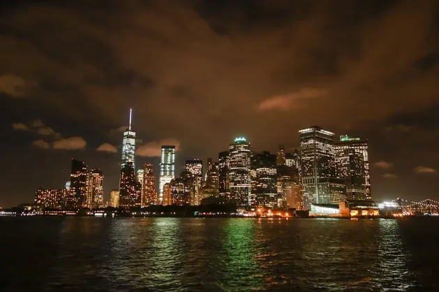 Lo skyline illuminato di una città con molti grattacieli di notte, visto dall'acqua.