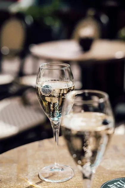 Due flûte da champagne con mirtilli poggiate su un tavolo in un caffè con sfondo sfocato.