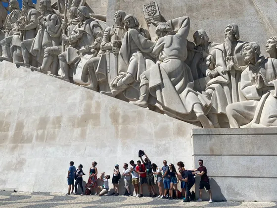 Un viaggio di gruppo WeRoad in posa per una foto alla base di un grande monumento di pietra con figure scolpite.