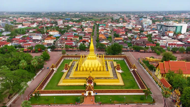 Una vista aerea di un grande tempio dorato con uno stupa centrale, racchiuso da mura e circondato da una città estesa.