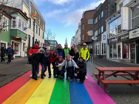 Un viaje en grupo de WeRoad posa para una foto en una calle pintada con colores del arcoíris, rodeado de edificios de la ciudad.