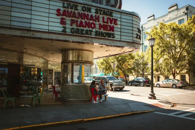 A classic theater entrance with a large marquee advertising 'Savannah Live' on a sunny street corner.