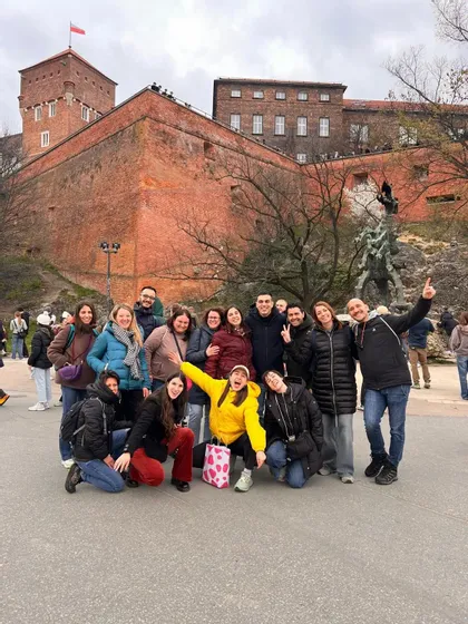 Un gruppo WeRoad in viaggio posa per una foto davanti a una grande fortezza di mattoni rossi e una statua di drago.
