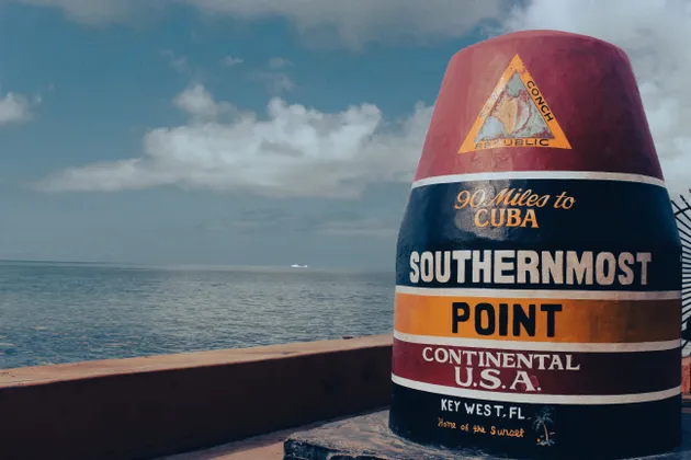 Der Bojenmarker am südlichsten Punkt in Key West, Florida, steht am Meer unter einem bewölkten Himmel.