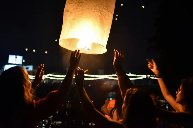 Un gruppo WeRoad, le cui sagome si stagliano su una grande lanterna di carta illuminata che stanno rilasciando nel cielo notturno.