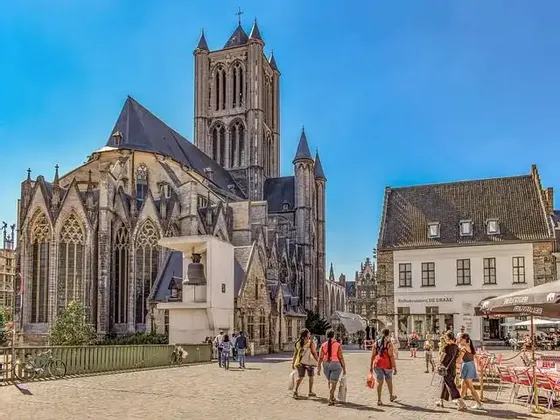 La gente camina por una plaza soleada con una gran catedral gótica y edificios históricos al fondo.