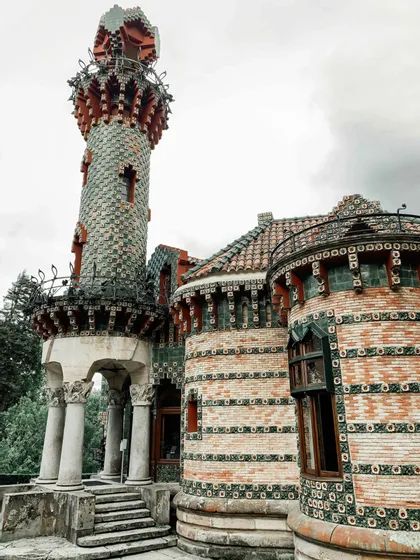 Un edificio decorato con un'alta torre rivestita di tegole verdi e rosse e muri in mattoni con motivi decorativi.