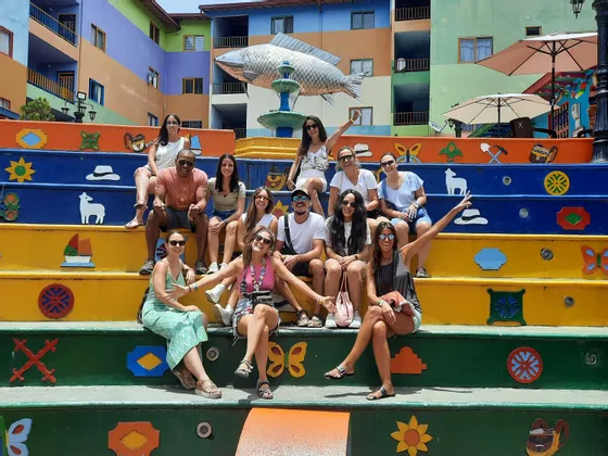 Un grupo de WeRoad posa para una foto en una amplia escalera de colores brillantes decorada con símbolos.