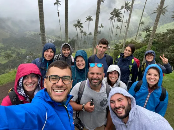 Un grupo de WeRoad se hace una selfie en un día de niebla, con un valle verde y altas palmeras de fondo.