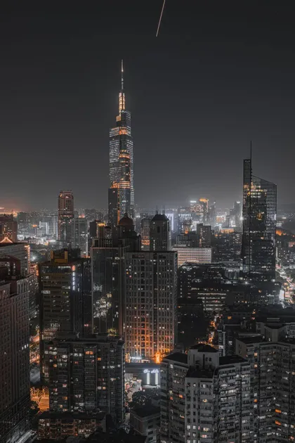 Un paesaggio urbano tentacolare di grattacieli illuminati di notte, con una torre prominente che si staglia nel cielo scuro.