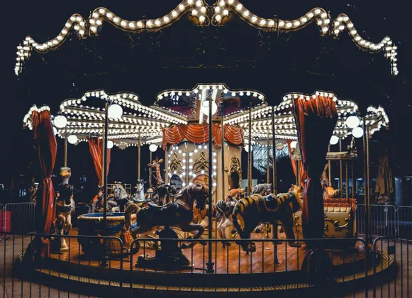 Una giostra in stile vintage con cavalli e una tigre è illuminata a giorno da fili di luci di notte.