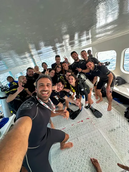 Eine WeRoad-Gruppenreise in Tauchausrüstung posiert für ein Gruppenselfie an Bord eines Bootes.