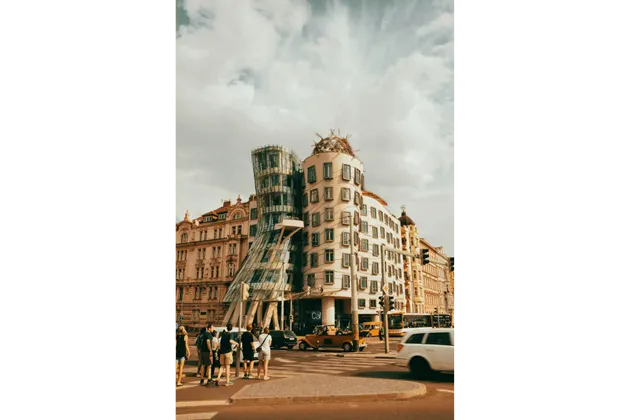 Un edificio dall'architettura decostruttivista, con una torre di vetro, si trova su una strada cittadina trafficata.