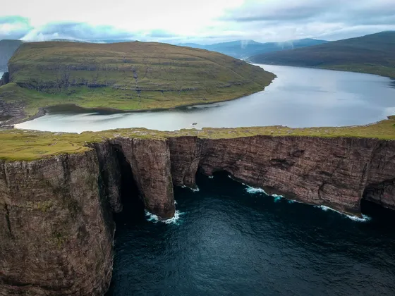 Veduta aerea di un grande lago su un altopiano erboso, a picco sull'oceano e accanto a scogliere rocciose.