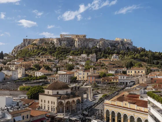 L'Acropoli si trova su una collina rocciosa che domina gli edifici storici e i tetti di Atene in una giornata di sole.