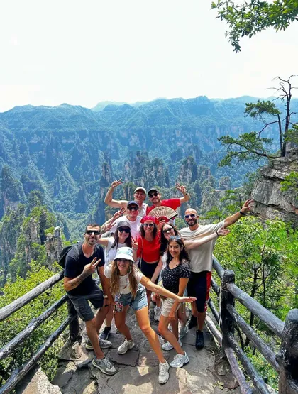 Eine WeRoad-Gruppe posiert gemeinsam an einem Berg-Aussichtspunkt vor der Kulisse hoher, säulenartiger Felsformationen.