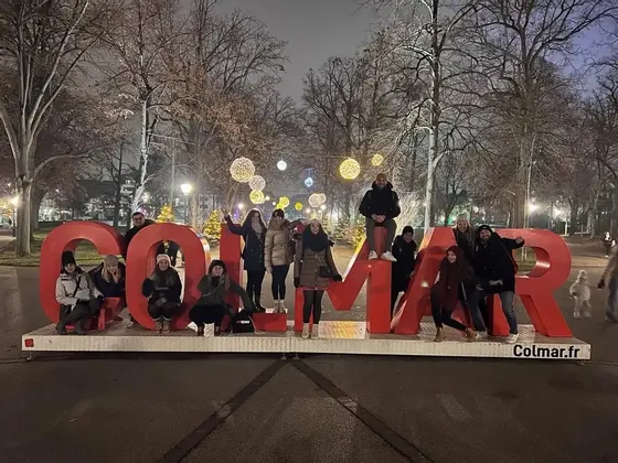 Un viaggio di gruppo WeRoad di persone in posa su grandi lettere rosse in un parco all'aperto illuminato di notte.