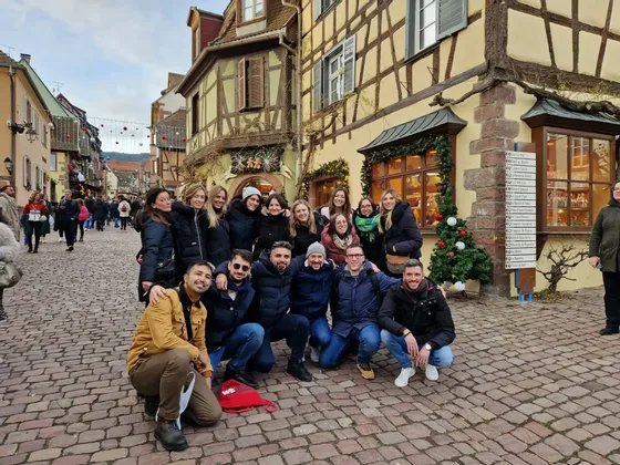 Eine WeRoad-Gruppe posiert für ein Foto auf einer Kopfsteinpflasterstraße vor Fachwerkhäusern mit Weihnachtsdekoration.