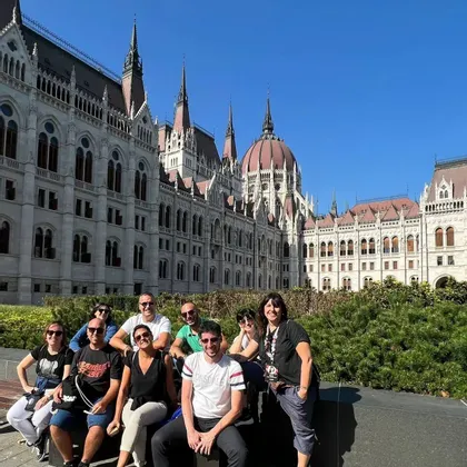 Un gruppo WeRoad si mette in posa per una foto su una panchina davanti a un grande ed elaborato edificio governativo.