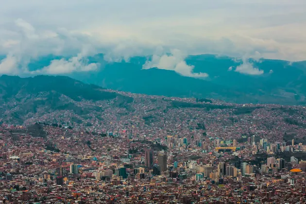 Una vista panorámica de una ciudad densa anidada en un valle entre montañas bajo un cielo nublado.